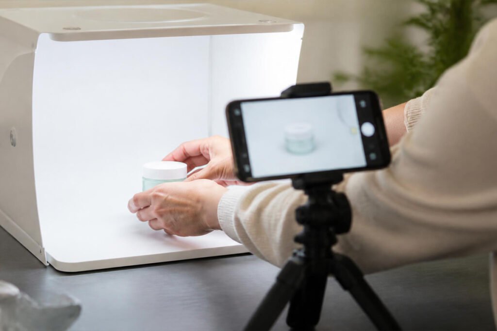 person photographing a product inside a light box with tripod